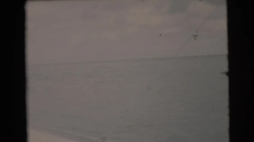 Faded 1956 8mm frame from a Miami-area boat outing, showing ocean, sky, and a faint horizon through worn film texture.