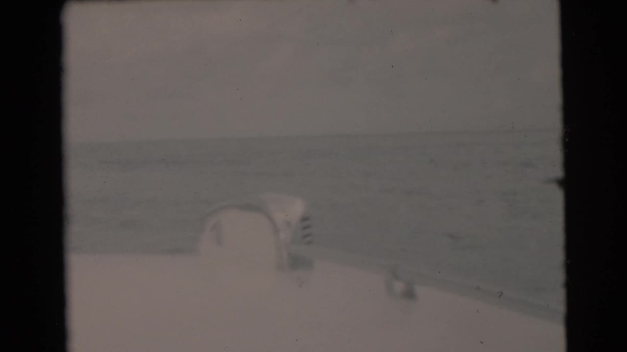 Soft 8mm view over a boat deck toward open ocean and hazy horizon.