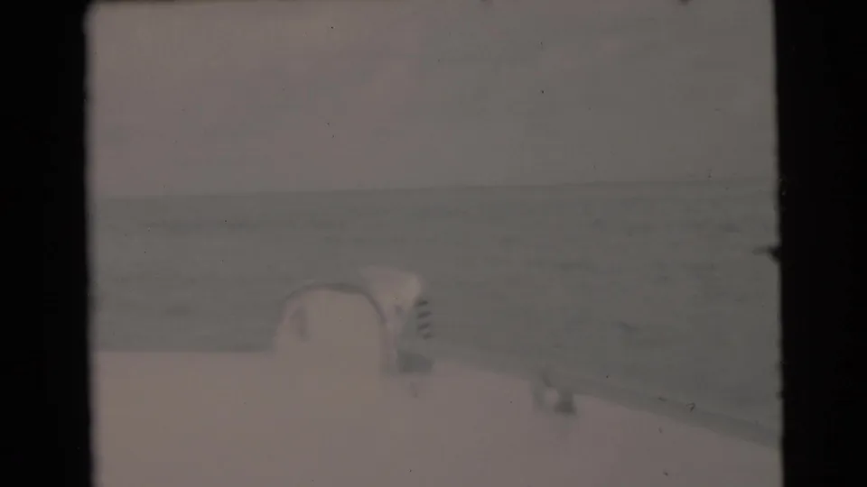 1956 Miami-area home-movie frame looking from a boat deck across open water under a pale sky.