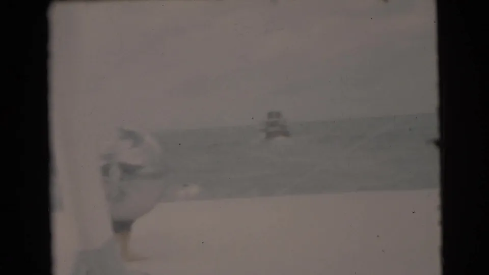 1956 Miami-area home-movie frame from a boat, showing open water and a distant vessel under hazy light.