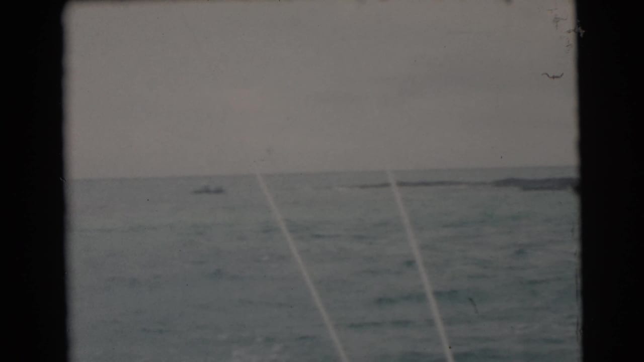 Open water with distant boats and pale fishing lines crossing the view.