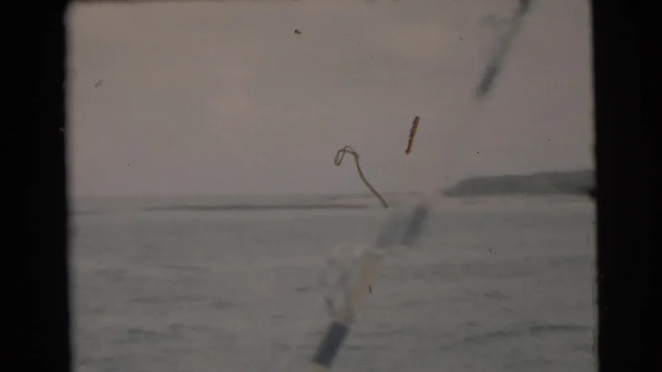 A 1956 Miami fishing-cruise view places rod or line hardware in the foreground against gray open water and a low horizon.