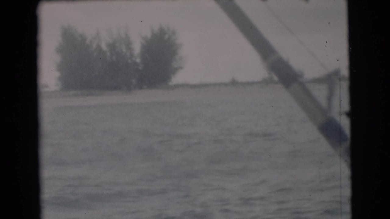 Open water seen through boat framing, with distant trees on a low shoreline.