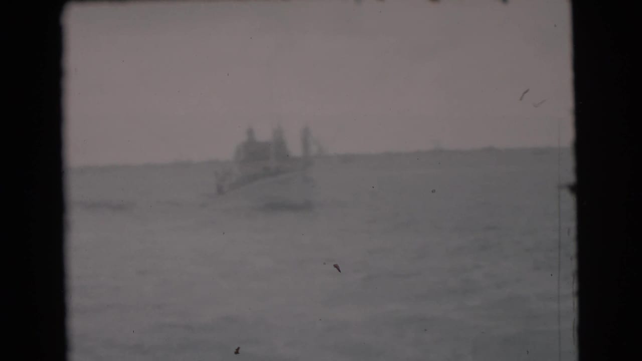 Hazy ocean horizon with a small distant boat near the center-left.