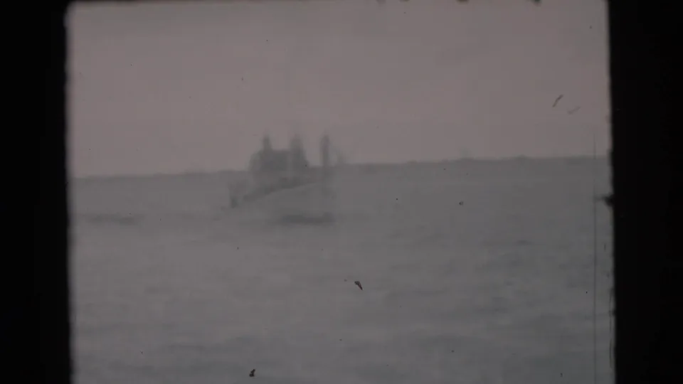 1956 Miami 8mm frame showing hazy ocean water and a small distant boat under a pale sky.