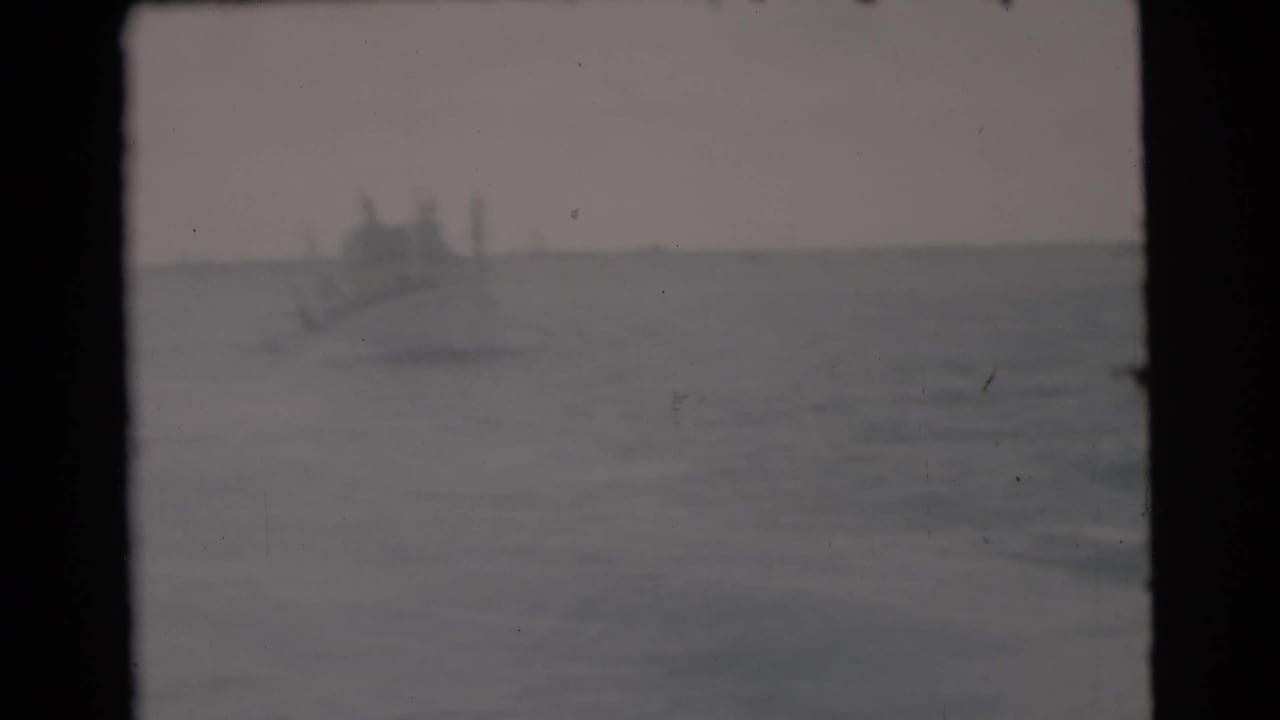 Small distant boat on open water beneath a hazy sky.