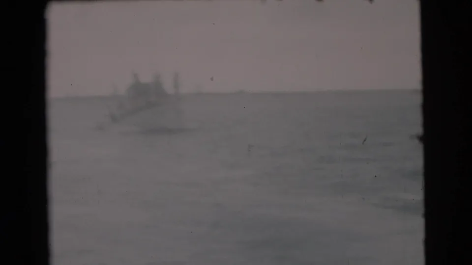 Distant boat silhouette on hazy Miami-area ocean water in a faded 1956 8mm home-movie frame.