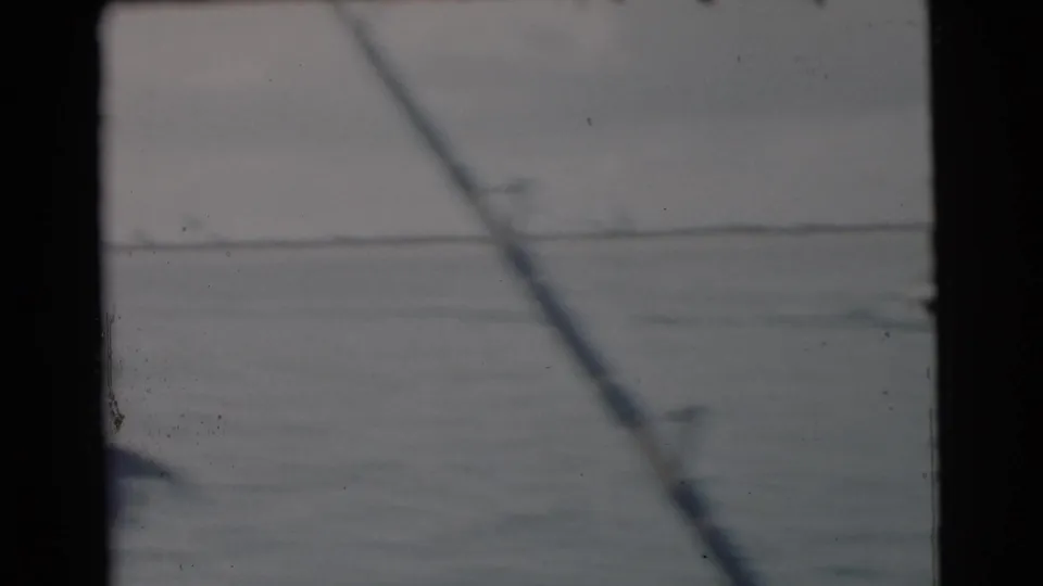 1956 Miami-area home-movie frame showing a fishing rod over open water beneath a low, pale horizon.
