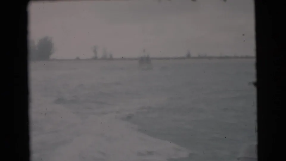 The final still shows wake behind the moving boat, open water, and a distant Miami shoreline with faint trees or structures.