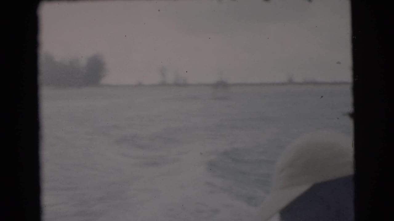Rear boat view over rippled water with a soft distant shoreline.