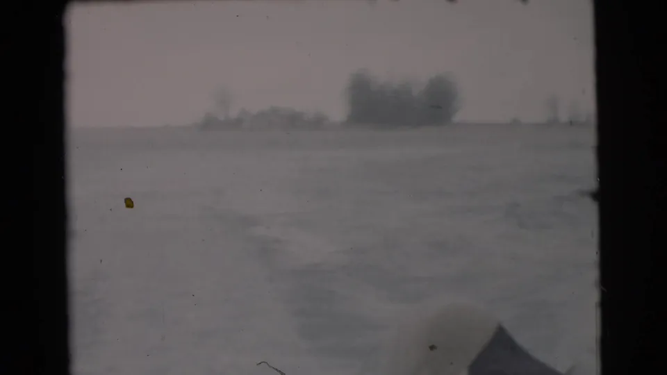 1956 Miami-area home-movie view from a moving boat, showing water, faint wake, shoreline trees, and a dark boat edge.