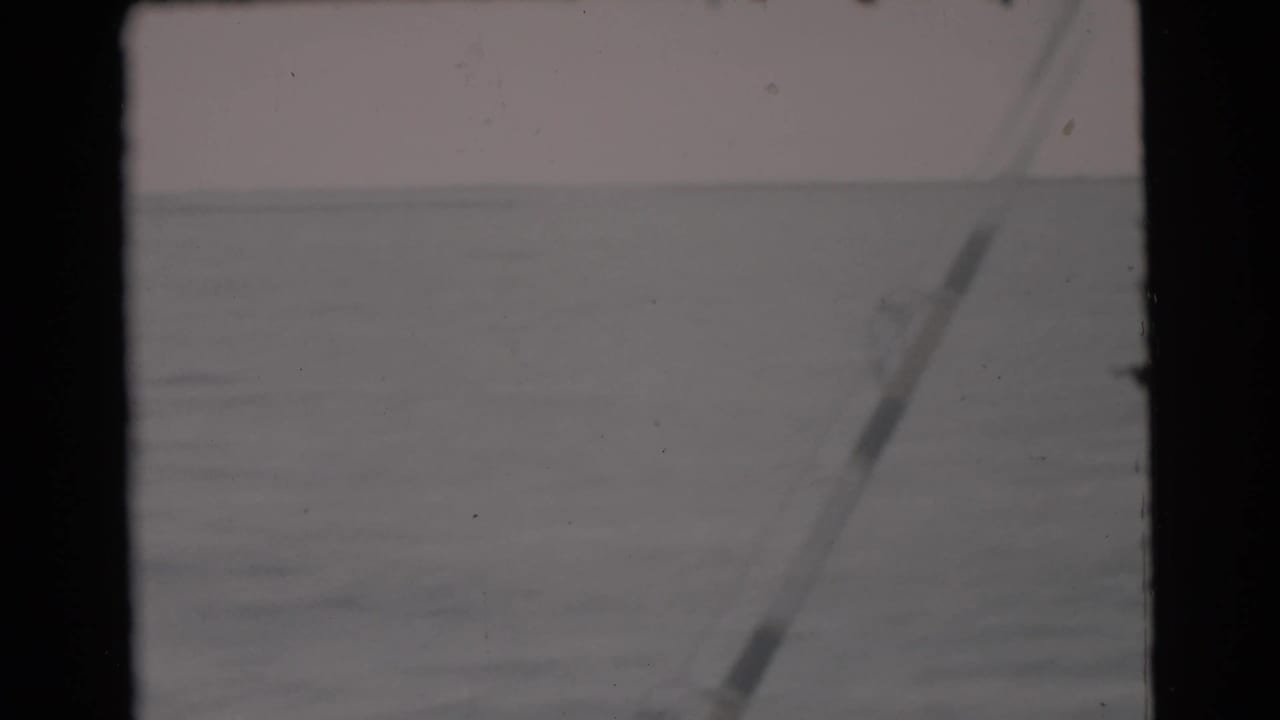 Open water seen from a boat with a hazy horizon and dark film borders.