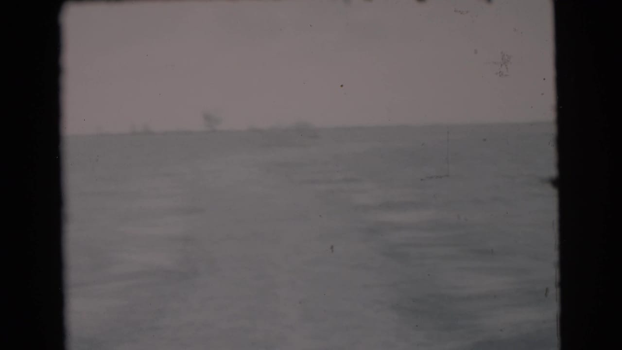 Choppy open water beneath a pale sky, seen through dark film-frame edges.