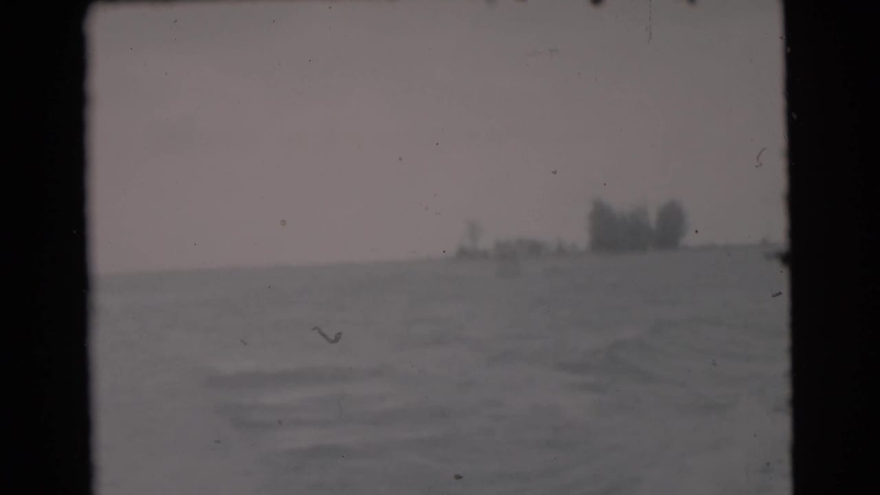1956 Miami-area boating footage showing gray-blue water, overcast sky, and indistinct distant shoreline or structures.