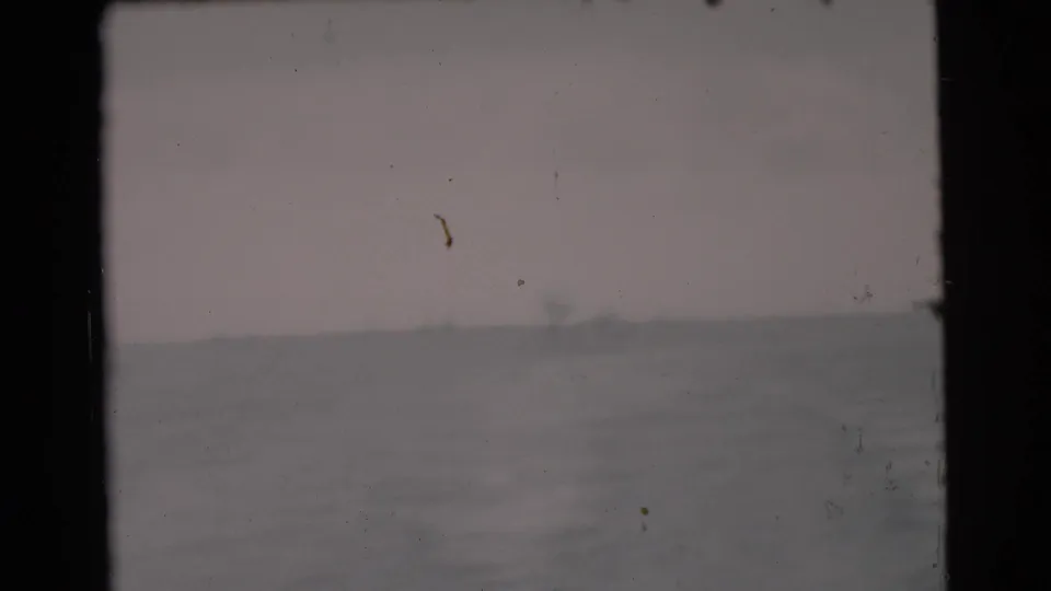 1956 Miami-area 8mm frame with washed, hazy water surface, low horizon, and visible dust and scratches from the film scan.