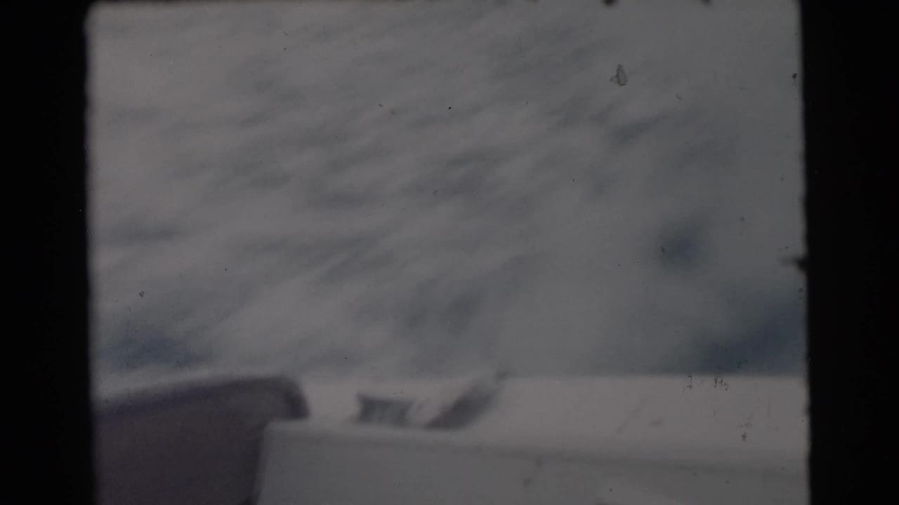 1956 Miami-area 8mm frame looking from inside or behind a boat window toward open water and a faint horizon.