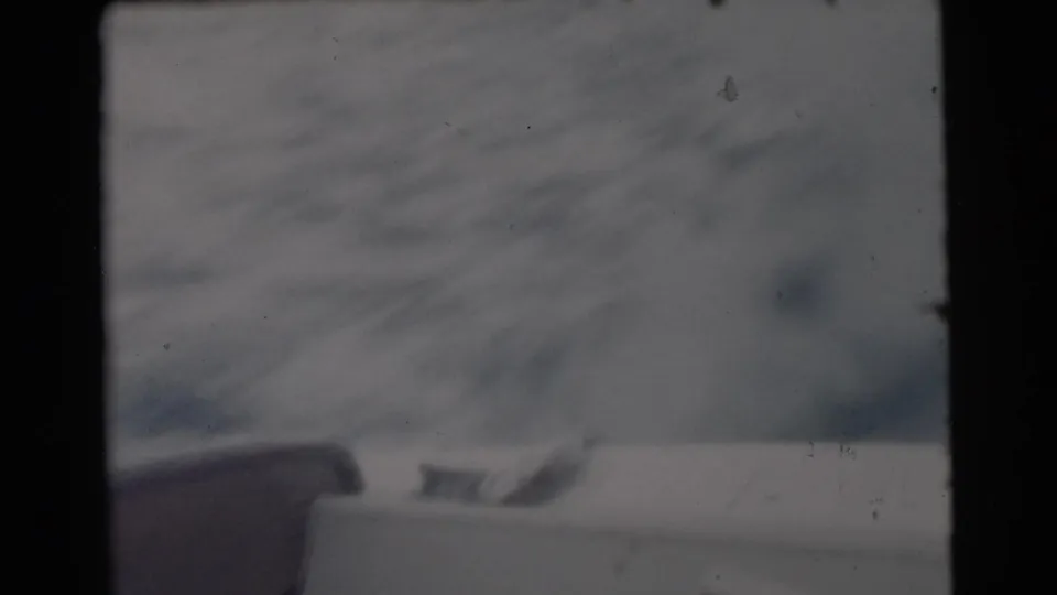 1956 Miami-area 8mm frame looking from inside or behind a boat window toward open water and a faint horizon.