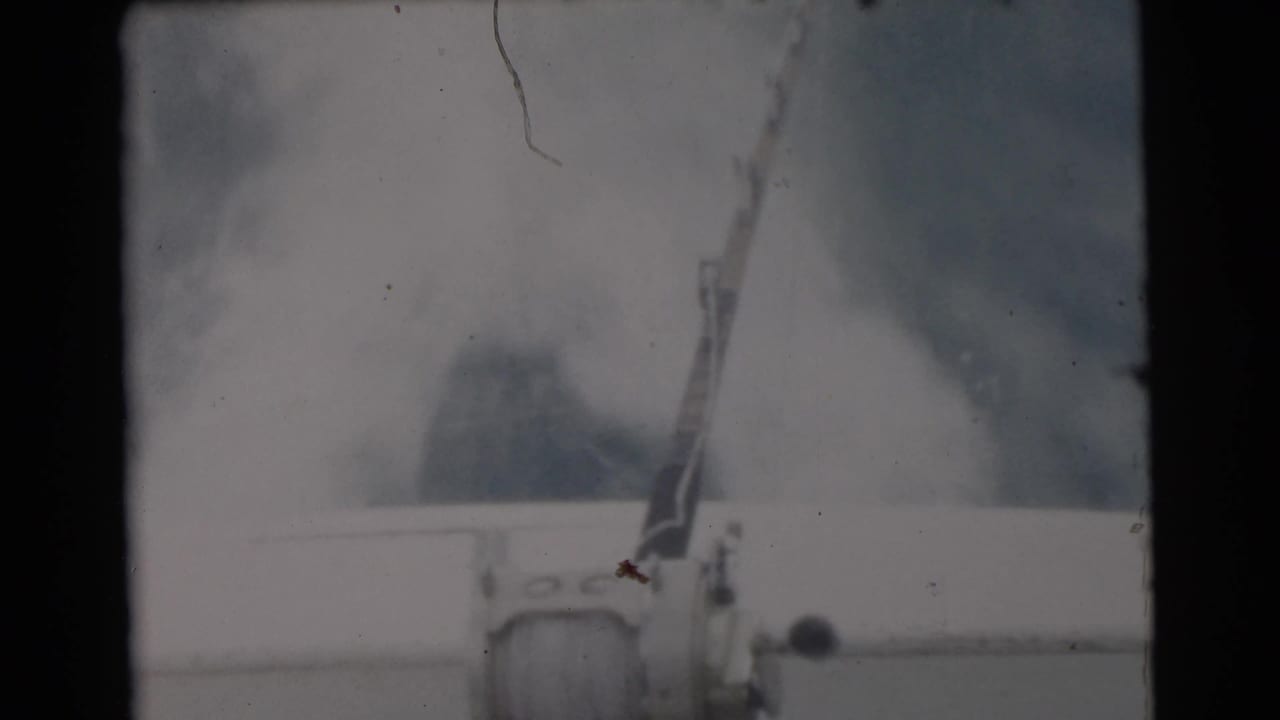 1956 Miami-area home-movie frame showing a mounted fishing rod and reel on a boat, with water and sky in the background.