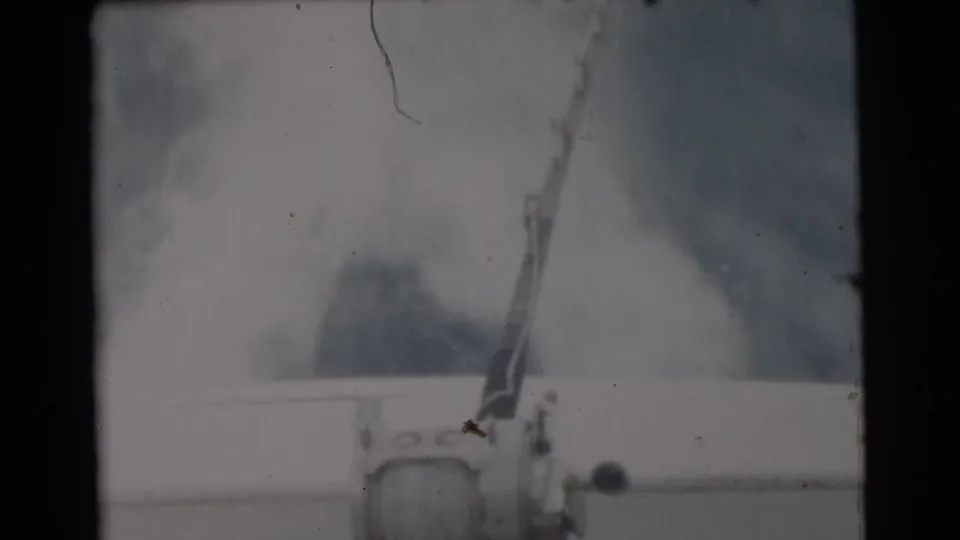 1956 Miami-area home-movie frame showing a mounted fishing rod and reel on a boat, with water and sky in the background.