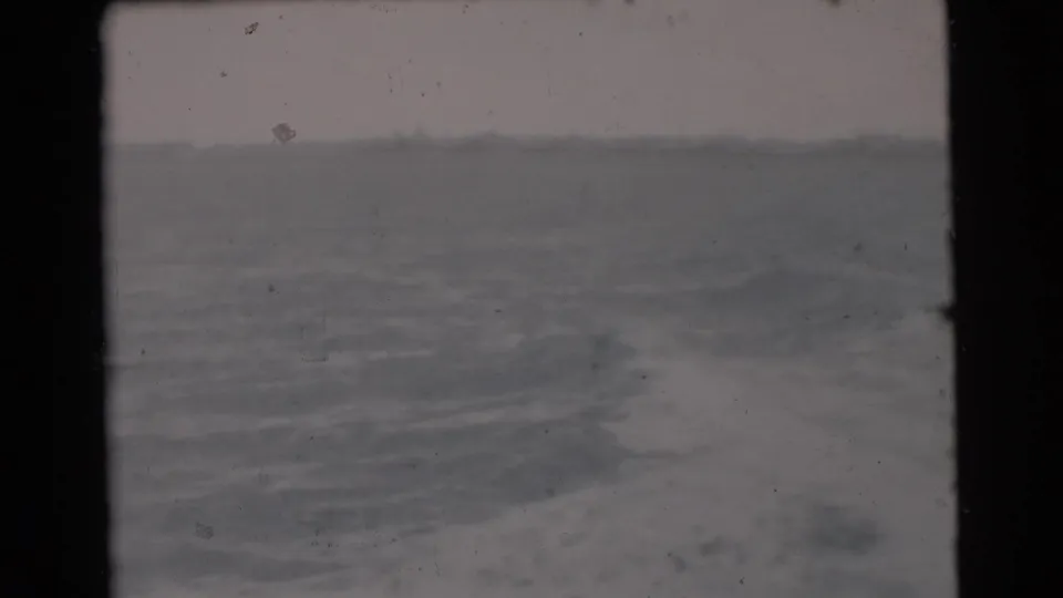 Miami-area 1956 8mm frame showing open water through a dark boat or film-frame edge, with grain and muted color.