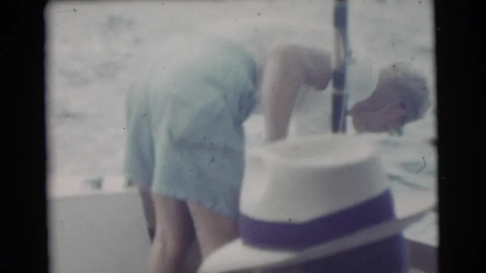 1956 Miami-area 8mm frame showing a man in a white fedora near the boat side, with water visible beyond.