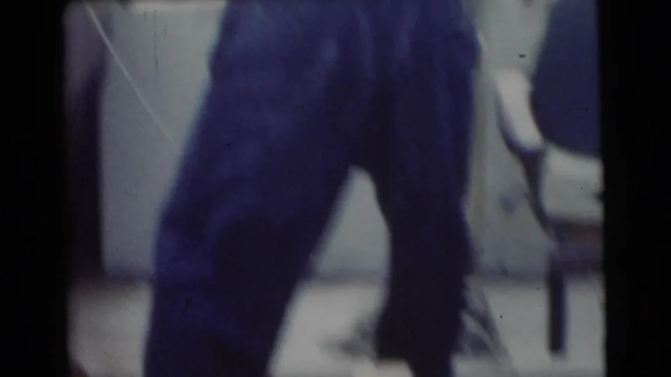 1956 Miami-area home-movie frame with a person in blue jeans standing on a boat, partially cropped by the handheld camera.