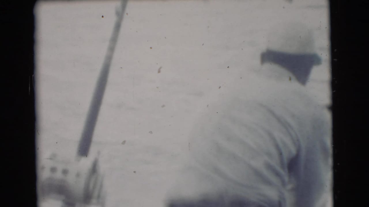 Man in a white shirt seen from behind holding a fishing rod on a boat.