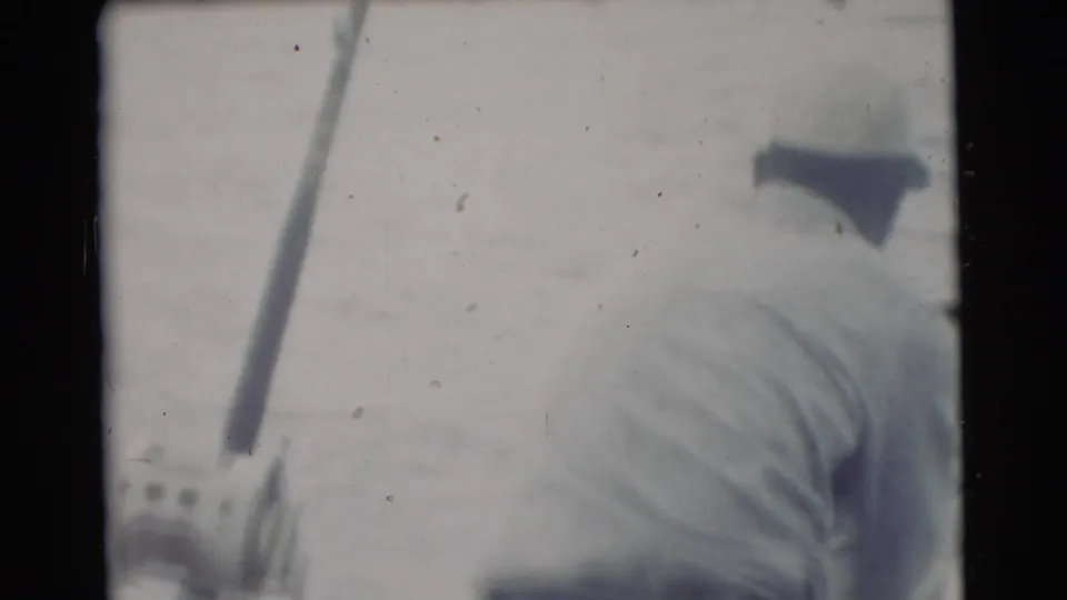 1956 Miami home-movie frame showing a fisherman from behind in a white shirt, with a rod angled upward near the water.