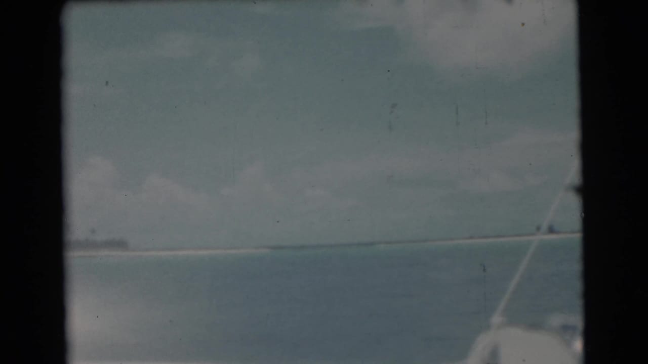 Open water and cloudy sky with a boat edge and rigging at the lower right.