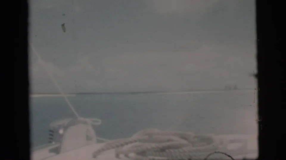 1956 Miami-area boating view with rope and deck hardware in the foreground and a pale island line across the water.