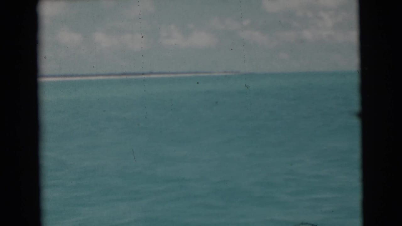 Turquoise ocean and distant horizon seen through dark 8mm film borders.