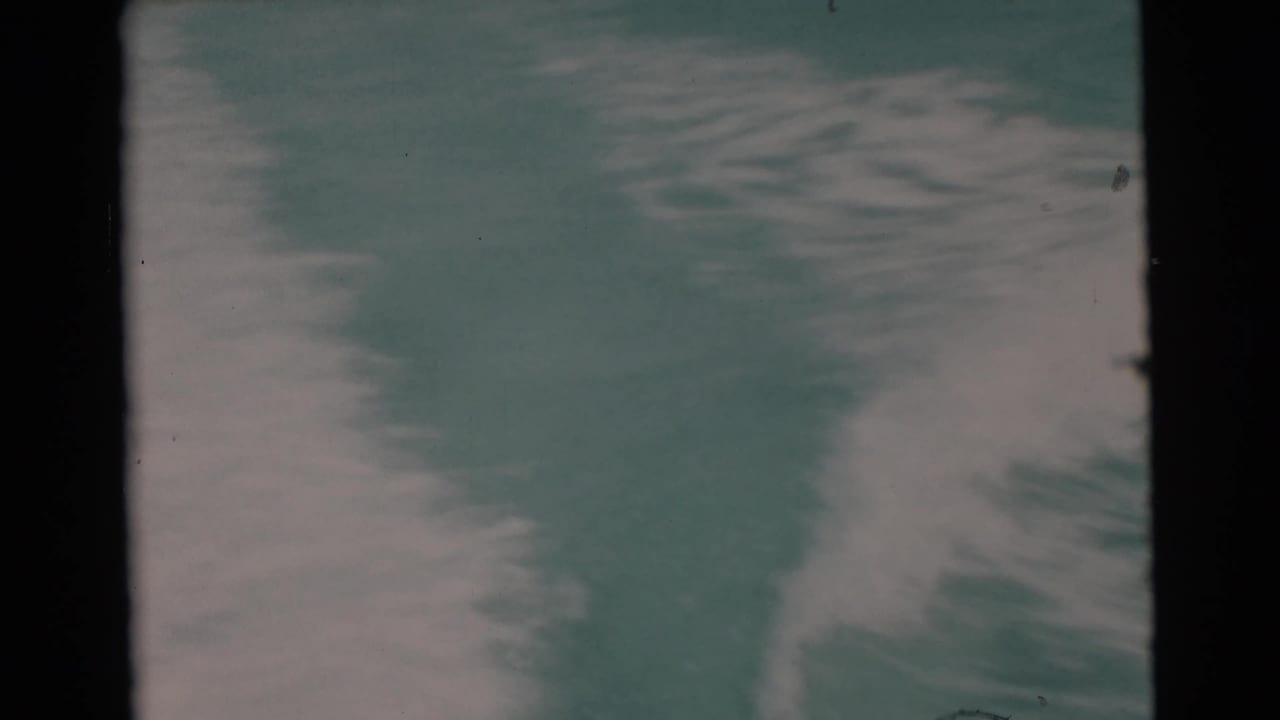 Foamy wake trails across turquoise water within the 8mm frame.