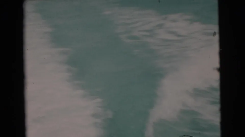 1956 Miami-area 8mm frame with pale boat wake spreading over teal ocean water, seen from a moving vessel.
