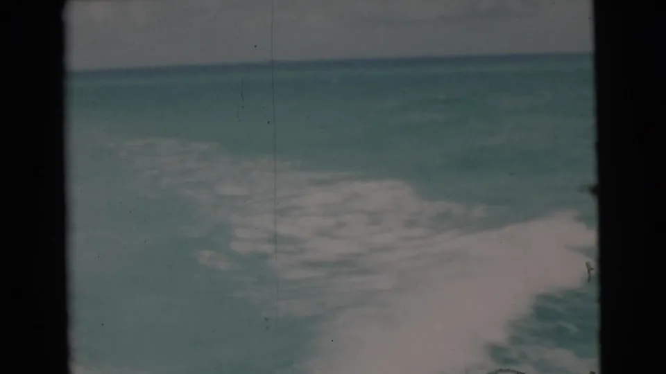 1956 Miami-area 8mm frame showing a distant horizon with white boat wake crossing the lower part of the sea view.