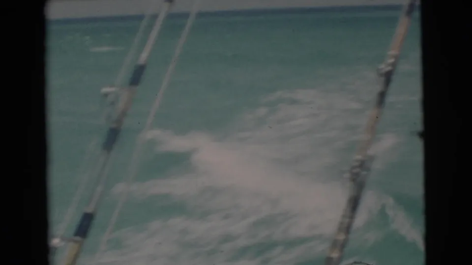 Home-movie view from a 1956 Florida fishing boat, with wake, rods or rigging, and choppy turquoise water filling the frame.