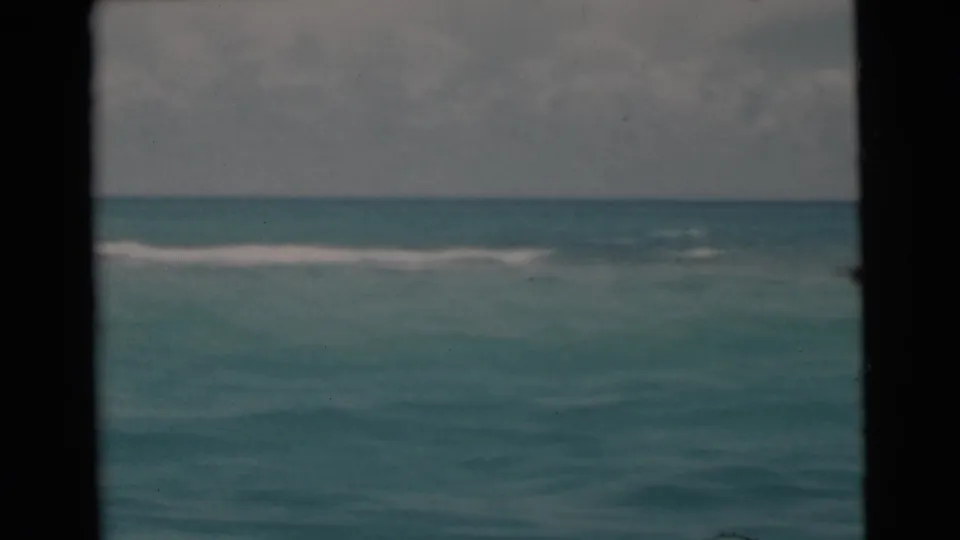 1956 8mm Florida coastal water view with a low horizon, pale wake, and overcast sky seen from a moving boat.
