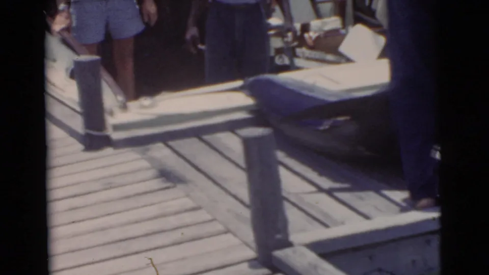 In 1956 Miami home-movie footage, men gather on a wooden dock as a large marlin lies partly in view near a boat.