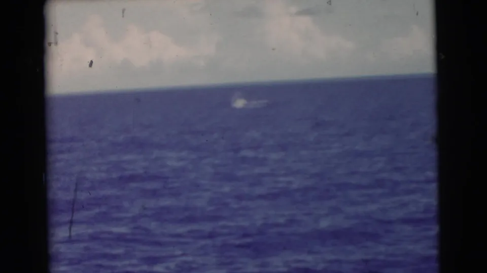 1956 Miami 8mm frame of open blue ocean and cloudy sky, with a small white object moving or floating in the distance.