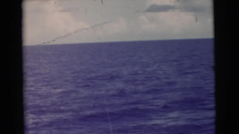 1956 Miami-area 8mm frame showing calm ocean water and a cloudy horizon from a boat or shoreline viewpoint.