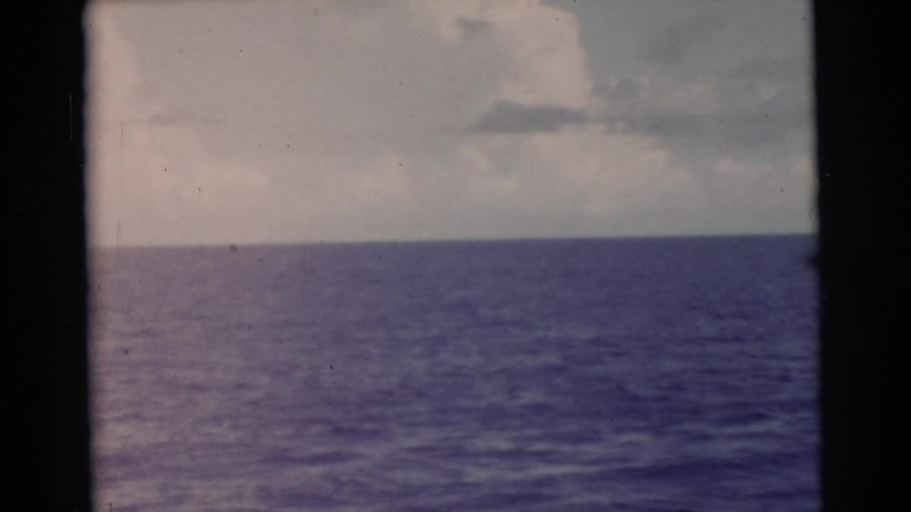 Ocean horizon and cloudy sky with visible film gate borders.