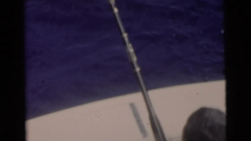 1956 Miami-area boating scene with a fishing rod angled over blue water and a person partly visible from behind.