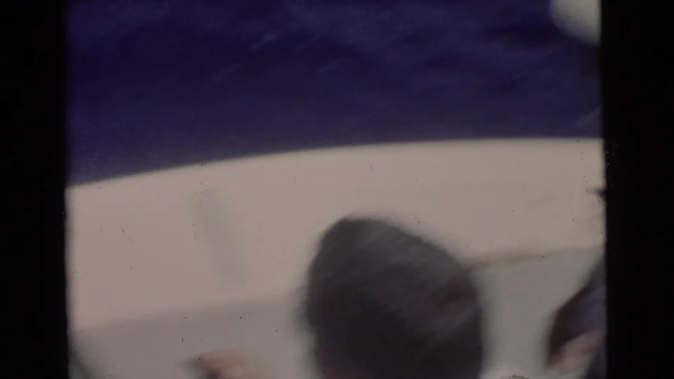 1956 Miami-area 8mm frame showing a person from behind near the boat edge while the ocean fills the background.