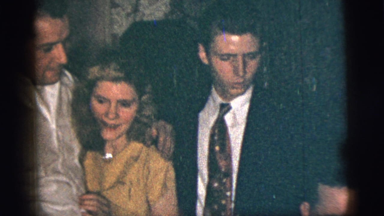 The woman faces the camera as the man in white and the suited young man remain close beside her in the 1956 New York City footage.