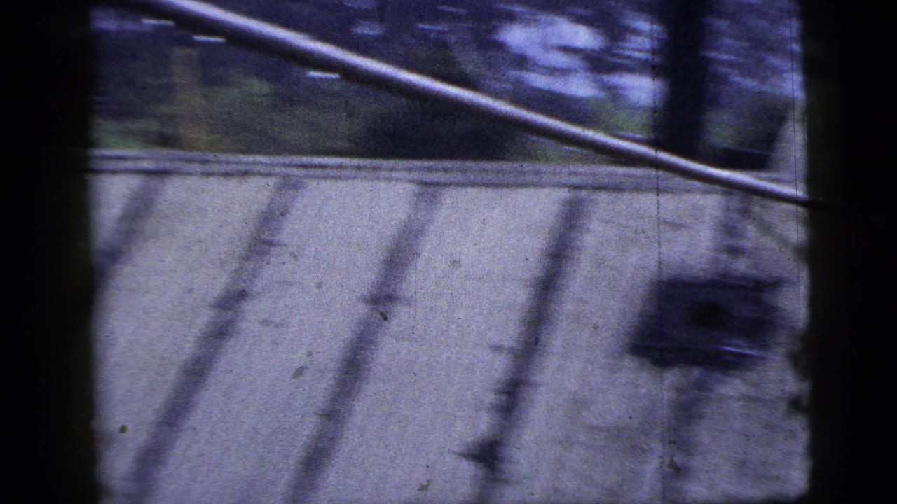 Slanted roof surface with utility line, dark foreground posts, and blurred background structures.