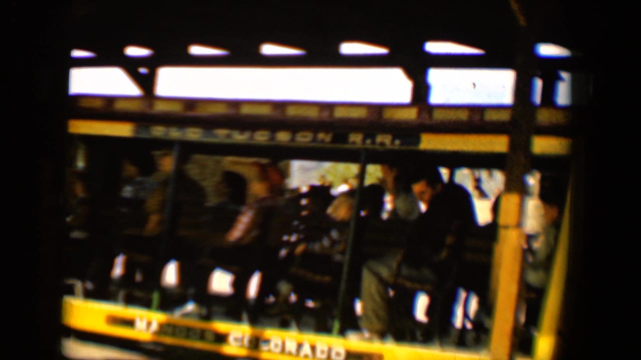1958 Tucson frame of riders seated in an open Old Tucson R.R. car, filmed with soft grainy 8mm color.