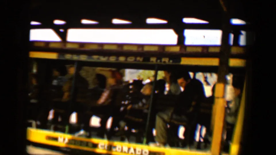1958 Tucson frame of riders seated in an open Old Tucson R.R. car, filmed with soft grainy 8mm color.