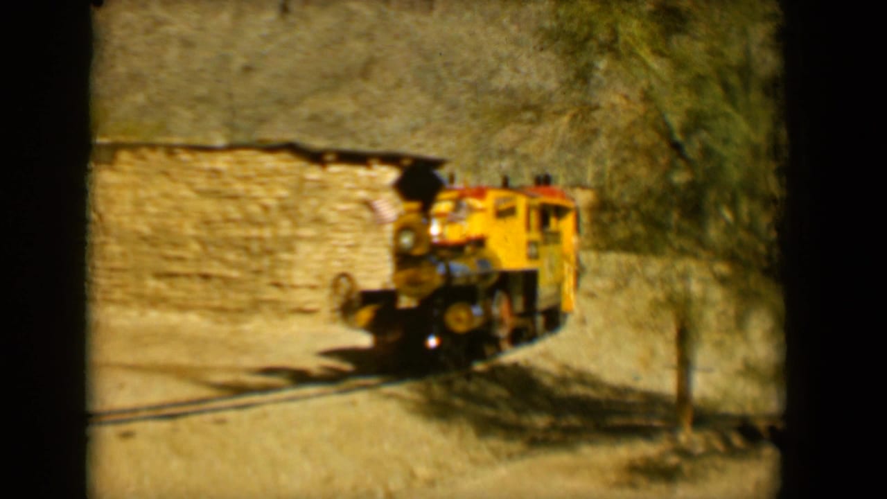 A yellow steam-style tourist train appears on narrow tracks in a rustic Tucson setting, 1958.
