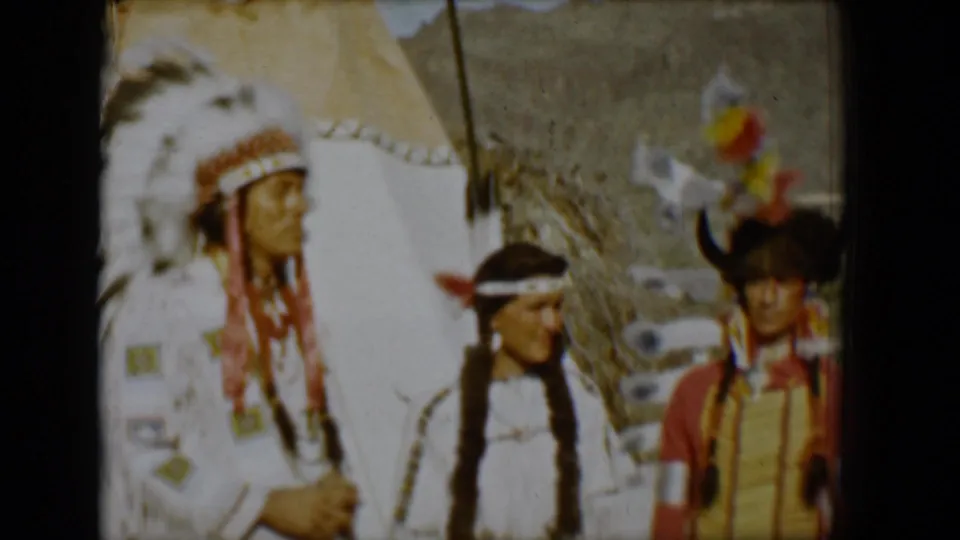Final 1958 Tucson frame showing the group beside a teepee, with feather details, beadwork, and mountains visible through faded 8mm color.
