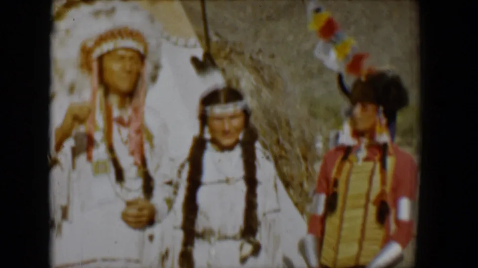 1958 Tucson frame showing three visible people in traditional regalia, with a tepee and mountainous desert background.