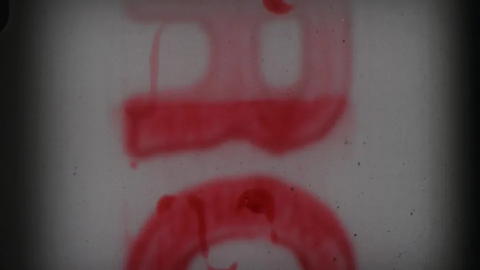 Soft 8mm frame with blurred red markings and a dark vertical gate edge, likely part of the reel opening.